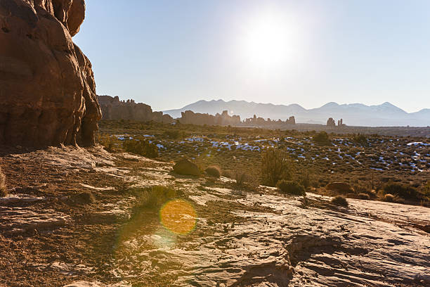 Beautiful golden desert terrain features scattered snow, rocky formations, and distant ranges under bright sunlight, capturing nature's raw beauty and serene atmosphere.