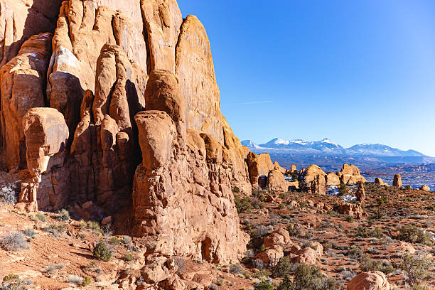 istock Desert Rock Formations Under Clear Blue Sky With Snow-Capped Mountains In Distance 2236282947