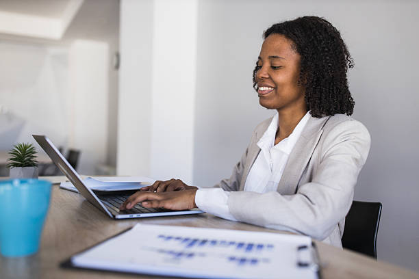 istock Black businesswoman smiling while typing on laptop in office 2236283919