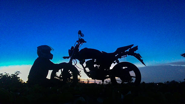 istock Silhouette of a Biker with Motorcycle at Sunset Against a Blue Sky 2236286468