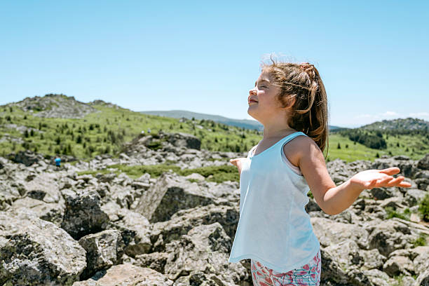 Child girl breathing fresh air in the summer mountain