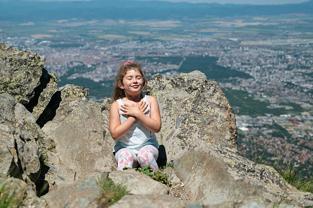 Child girl breathing fresh air in the summer mountain