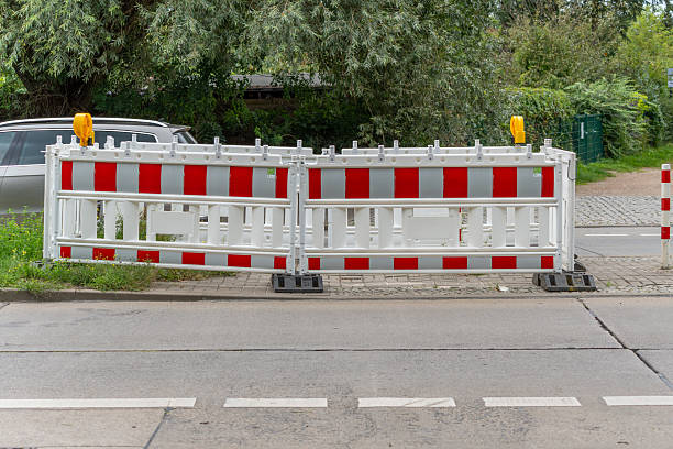 istock A red and white barrier blocks the sidewalk along a road. 2236291752