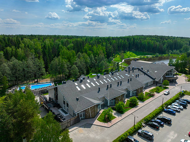 Suzdal, Russia - May 12, 2024: An aerial view of a long, modern hotel building with a grey roof, located next to a swimming pool and a dense green forest.