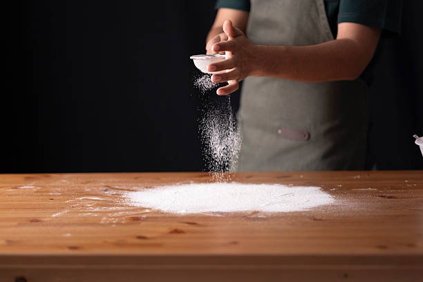 istock Person sifting flour on wooden table preparing for baking or cooking 2236295046