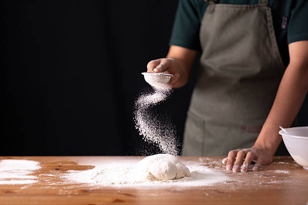 istock Person sifting flour onto fresh dough, preparing homemade bread in kitchen 2236295231