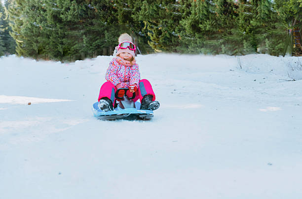 Little girl  having  fun on his sled in the winter mountain