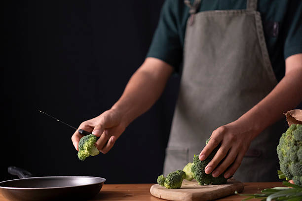 istock Chef dropping fresh green broccoli florets into a pan for healthy cooking 2236295532