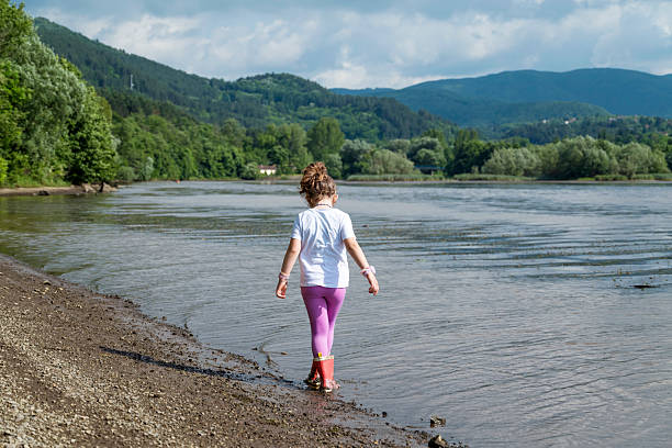 Child with rubber boots walking in the water of a lake