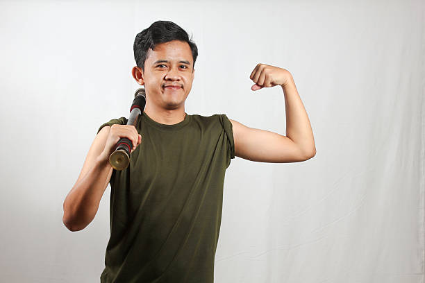 Asian man lifting light barbell while showing off bicep muscles isolated on white background