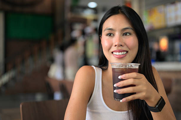 Young woman sitting and drinking iced coffee at restaurant