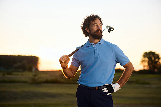 istock Golfer standing on a golf course at sunset and looking away. 2236313395