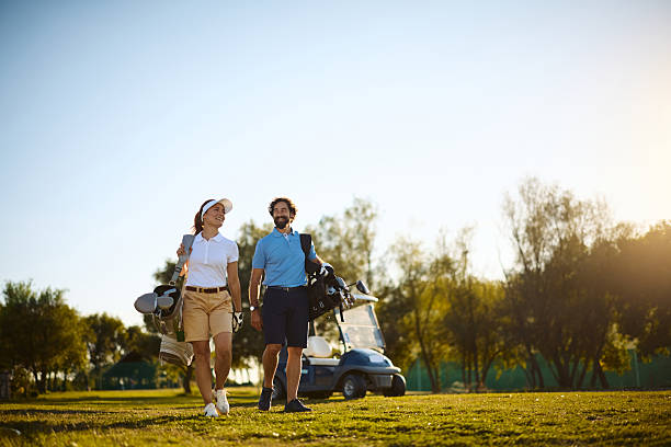istock Happy couple with golf bags walking across the course. 2236313647
