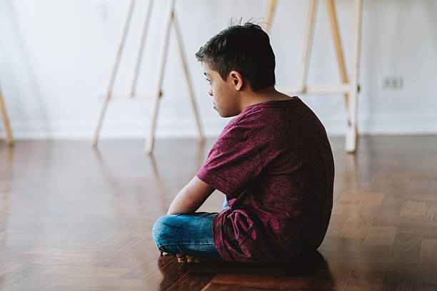 istock Child with Down syndrome sitting alone on the floor 2236313731