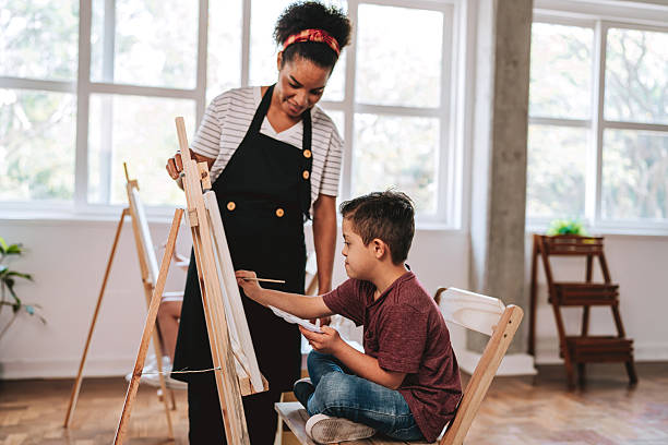 istock Teacher assisting a child with Down syndrome - painting class on canvas 2236313772