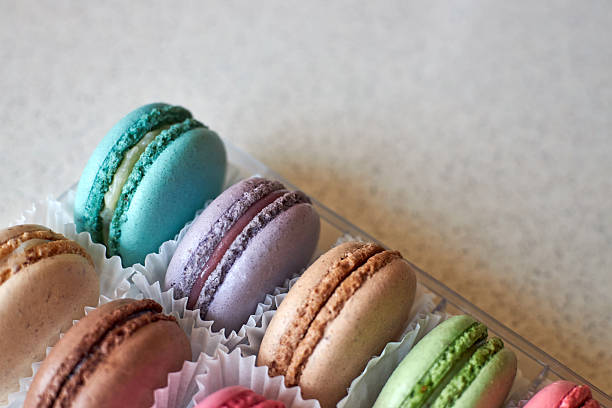 Bright colorful cakes French Macarons with white paperpan in plastic box