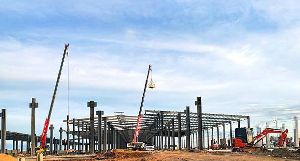 istock Factory industrial building metal framework with workers and crane trucks are working in construction site against blue sky background 2236317882