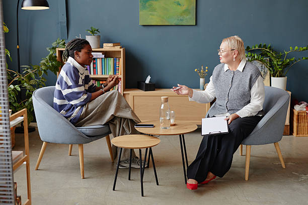 istock Young Black Man Talking with Middle Aged Caucasian Female Therapist Indoors 2236318749