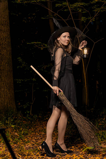 istock Halloween witch with lantern and broom walking in dark forest at night 2236319591