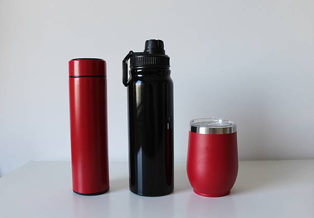 Close-up of hiker pouring hot drink from thermos into travel mug in the snowy forest