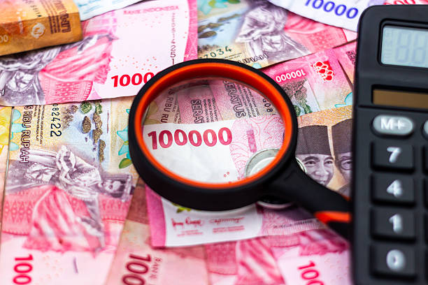istock Analyzing Indonesian Rupiah Currency with Magnifying Glass and Calculator for Financial Planning and Economic Analysis highlighting Banking Investments and Monetary Strategy 2236324339