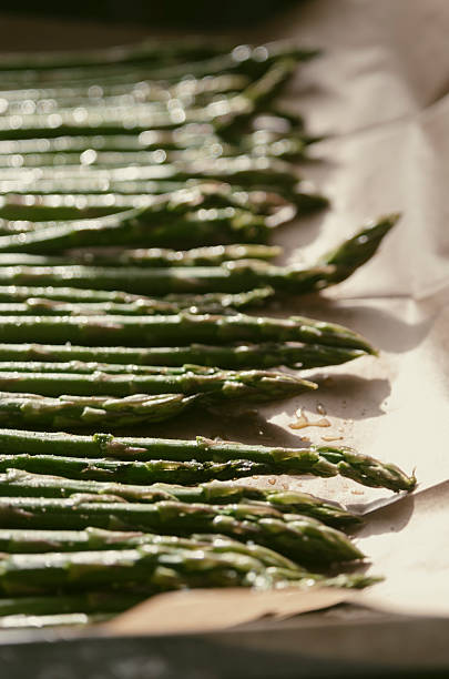 istock Freshly prepared asparagus spears arranged on parchment paper ready for roasting in an oven 2236325727