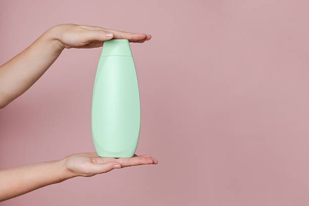 istock Elegant hand with shampoo light bottle isolated on solid pink background. Package for cosmetics product, your brand, spa, beauty. Space for text 2236325967