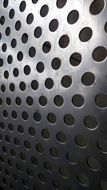 istock Stainless Steel Mesh Displays Intricate Pattern of Perforations and Reflections in Bright Light 2236328071