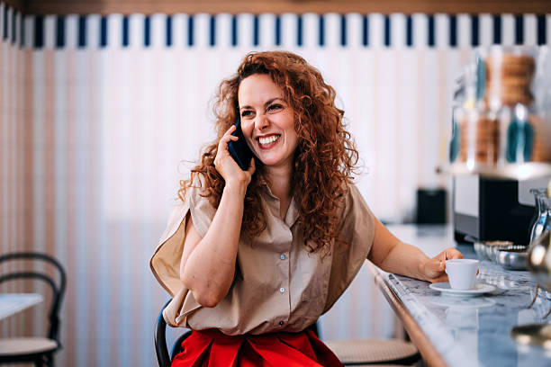 istock Smiling Woman Speaking on Phone While Enjoying Coffee in a Cafe 2236328678