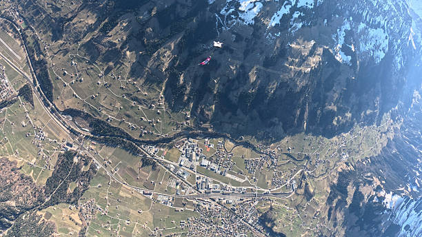 Trapeze fliers leave plane, soar above mountain landscape, Bern Canton
