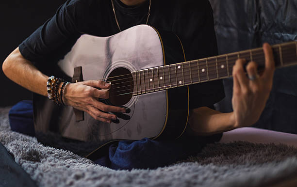 istock Young man playing a guitar at home 2236330488