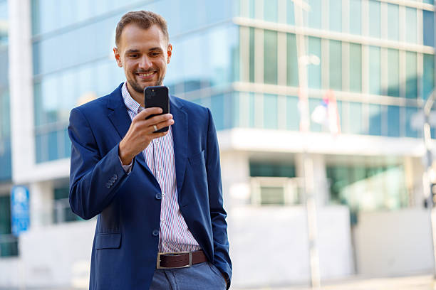 istock Businessman smiling while using smartphone in a city, connecting with technology and modern communication 2236333201