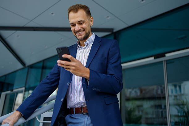 istock Smiling businessman using mobile phone, checking messages, staying connected, modern technology, urban setting 2236333325