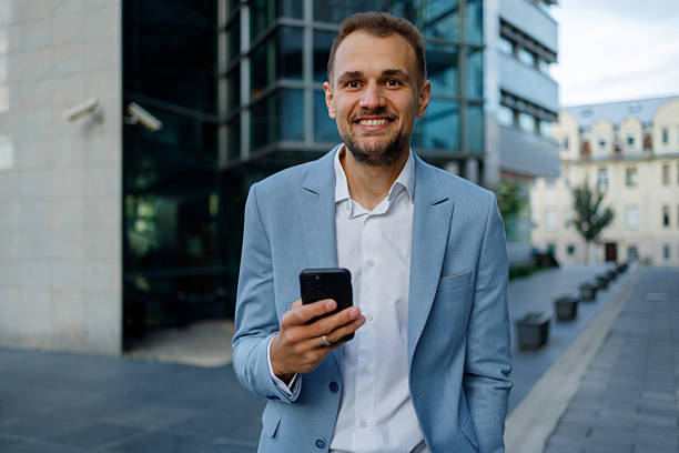 istock Smiling businessman using smartphone in city, reflecting success and digital connectivity in modern urban life 2236334165