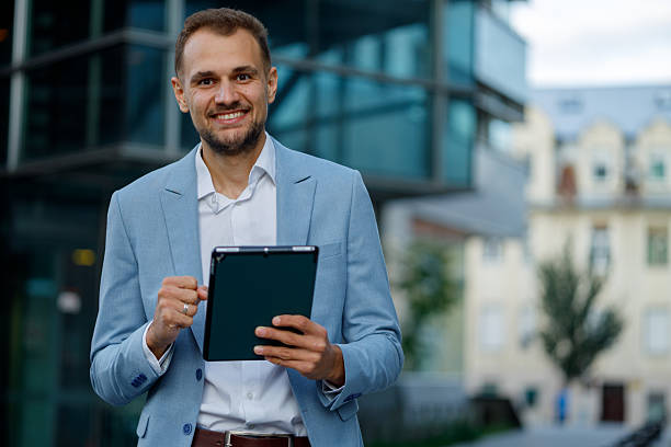 istock Happy businessman using a digital tablet for remote work, staying connected and productive in a modern city environment 2236334233