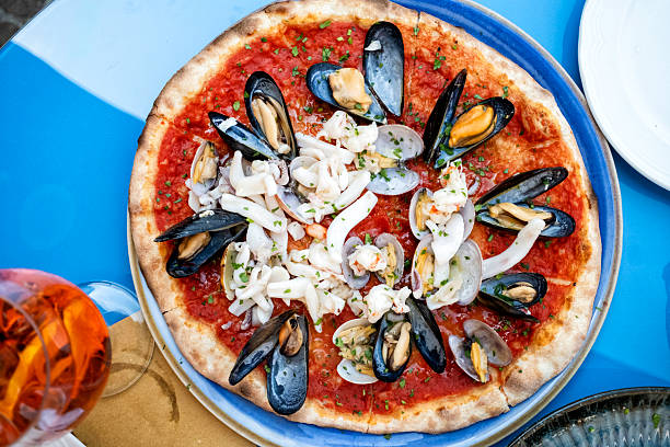 Delicious mediterranean seafood pizza with scallop, shrimps and mussels served on wood. Italian food,