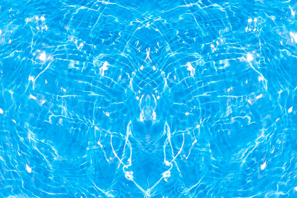Blue water with ripples on the surface. Defocus blurred transparent blue colored clear calm water surface texture with splashes and bubbles. Water waves with shining pattern texture background.