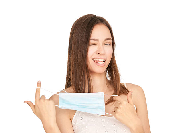 istock Young caucasian female winking and holding face mask with playful expression 2236339728
