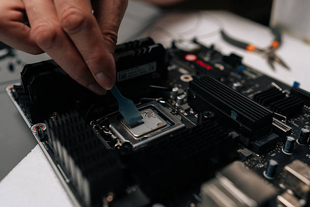 istock Close-up cropped shot of technician hands applying thermal paste to CPU of computer motherboard, ensuring optimal heat dissipation during maintenance or upgrade service 2236339902