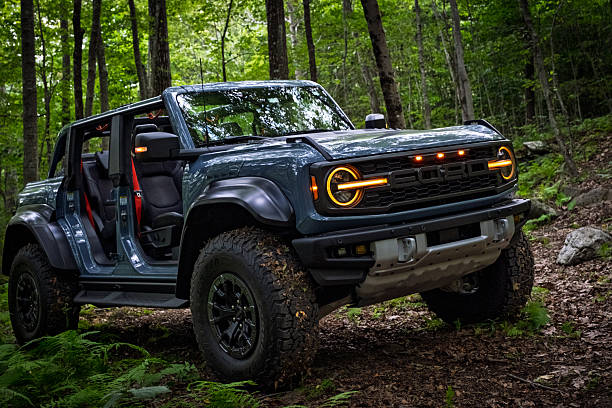 Colchester, Connecticut, USA - 08-28-2025  A 2025 Ford Bronco Raptor withAzure Gray Metallic Tri-Coat paint parked off-road in a forest with doors removed, showcasing rugged design, off-road capability, and adventure lifestyle appeal.