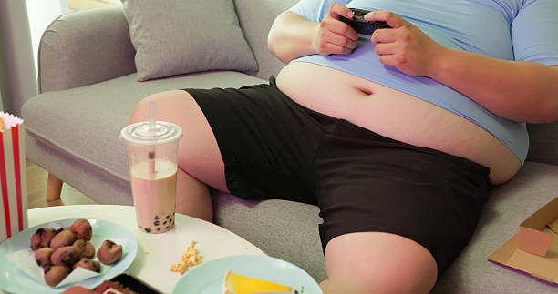 istock obese man eating junk food at home 2236346718