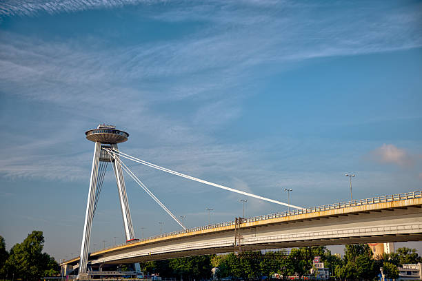 Bratislava, Slovakia – July 24, 2025: The UFO Observation Tower atop the SNP Bridge spans the Danube River under a bright morning sky.