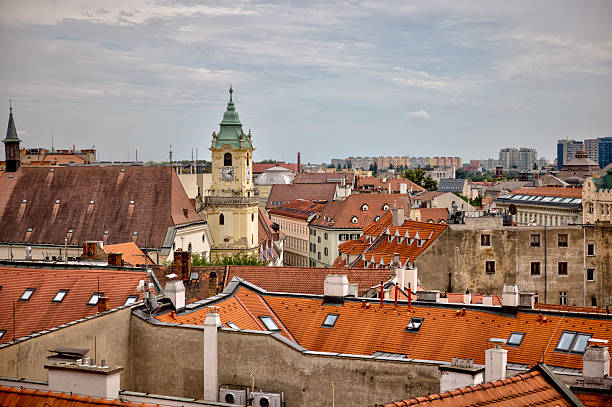 Bratislava, Slovakia – July 24, 2025: Rooftop view over Bratislava’s Old Town reveals a patchwork of tiled gables, dormer windows, and colorful facades, blending Baroque and modern elements across a layered skyline of residential and religious architecture.