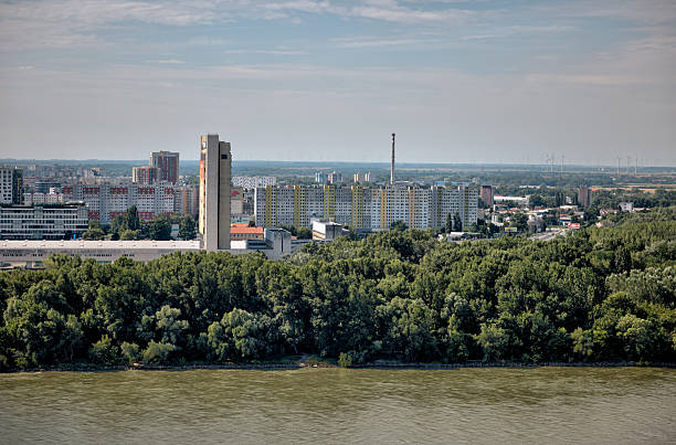 istock Panoramic view over Bratislava from the castle hill, with St. Martin’s Cathedral in the foreground, the Danube River winding through the city, and modern high-rises forming the skyline under a bright summer sky. 2236357250
