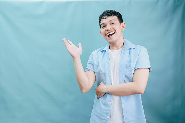 istock Cheerful Young Man Gesturing with a Smile in a Light Blue Background Captured in a Joyful Moment 2236360054