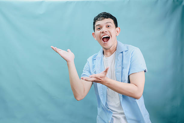 istock Joyful Young Man Expressing Excitement with Bright Smile Against Blue Backdrop in Studio 2236360077
