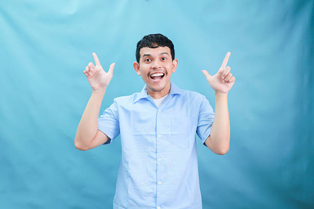 istock Cheerful Young Man Gesturing with Excitement Against a Light Blue Background in a Playful Mood 2236360823