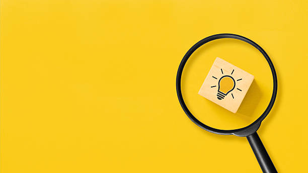 istock Creative idea concept, magnifying glass and light bulb icon on wooden block with yellow background 2236369268