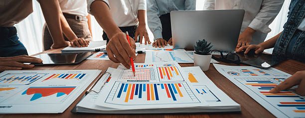 istock Focus financial report papers with blurred analyst team working. Scrutinize 2236370339