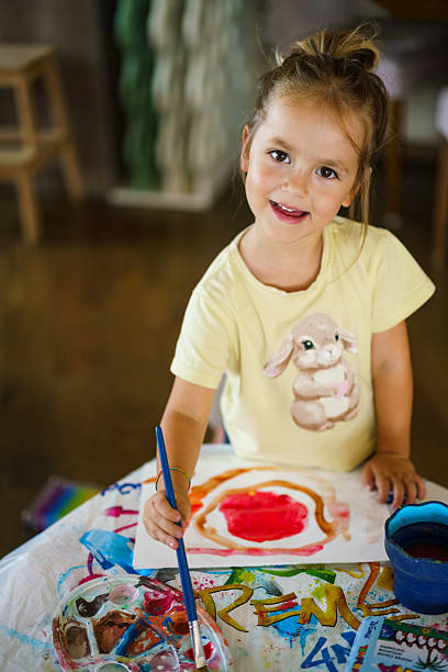 Happy girl painting with watercolors, showing childhood creativity.